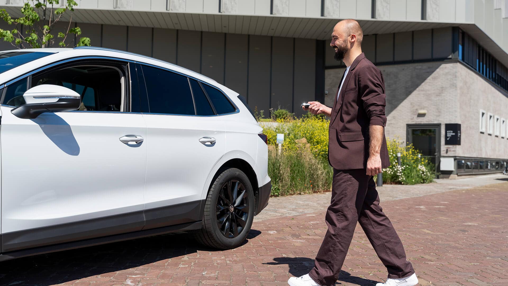 Ondernemer loopt met autosleutel naar zijn witte leaseauto – symbool voor het afsluiten van een financial lease via Watkanikleasen.nl.